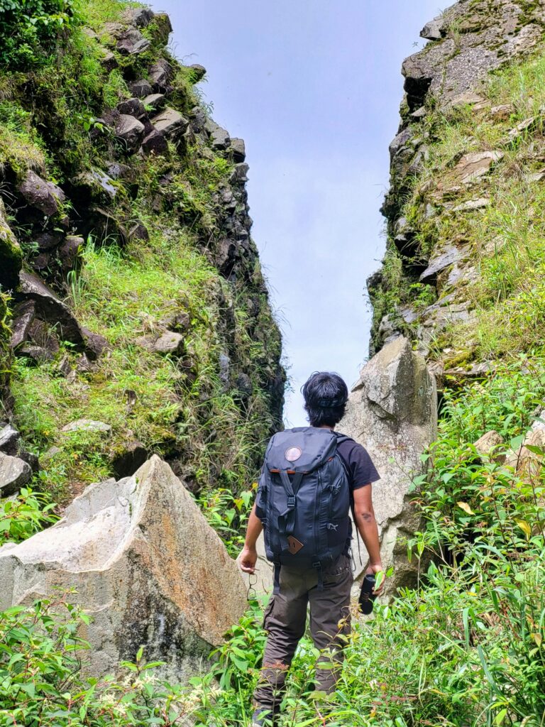 A hiker explores the rocky terrain of Dzukou Valley, capturing the spirit of adventure and nature.